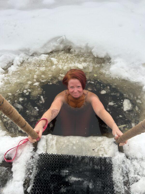 Woman enjoying an ice bath in a frozen lake during a winter wellness and cold therapy retreat