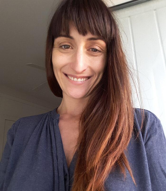 Portrait of Melissa smiling in natural light at a peaceful wellness retreat and community space