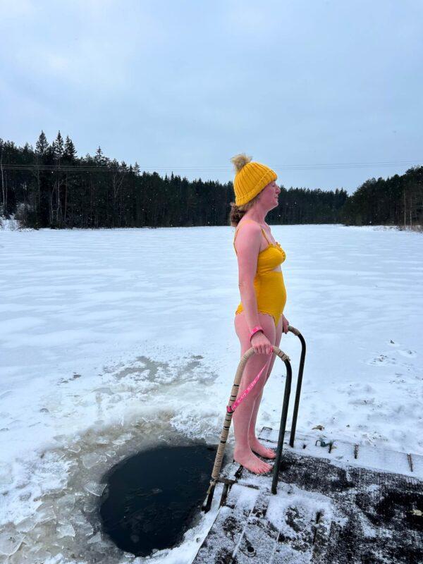 Woman standing beside an ice bath on a frozen lake during the Wild Winter Retreat at Shambala Gatherings