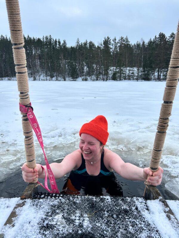 Retreat participant smiling during an ice bath in a frozen lake at Shambala Gatherings