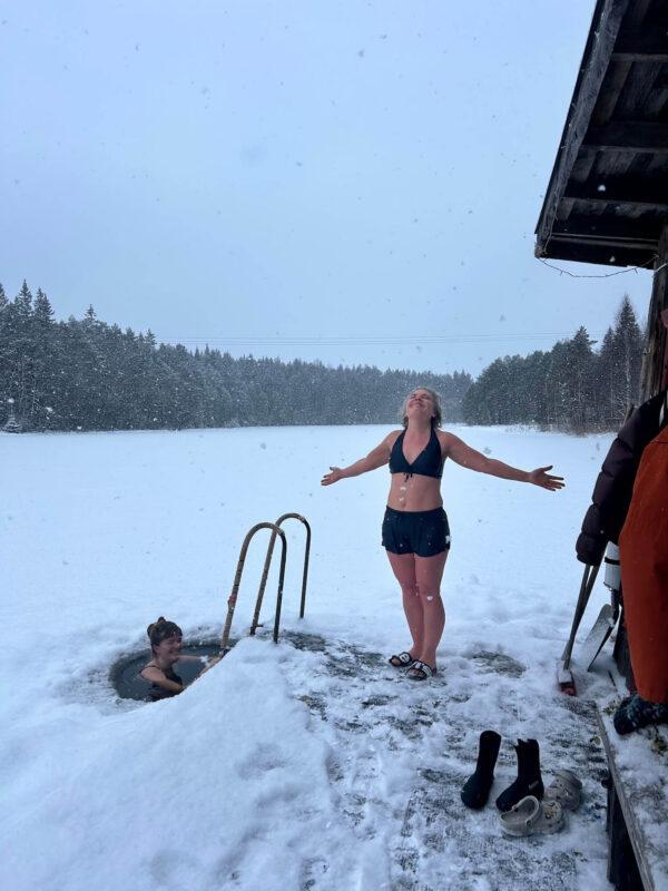 Woman enjoying an ice bath beside a frozen lake during the Wild Winter Retreat at Shambala Gatherings