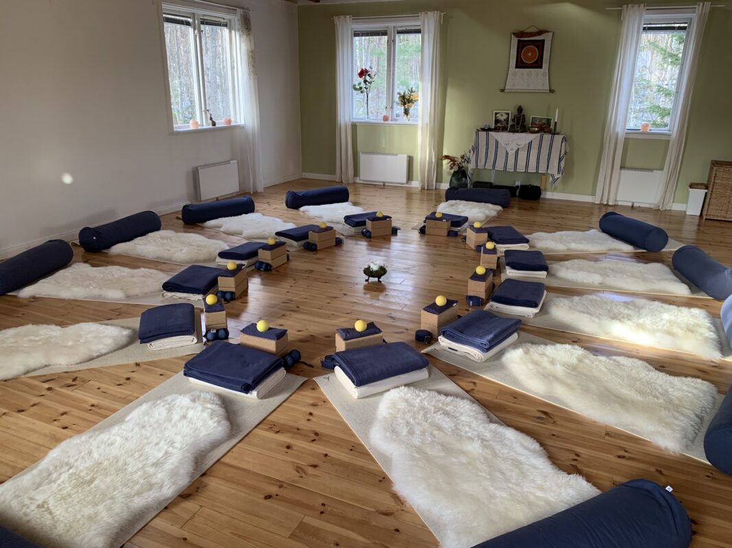 Yoga mats, bolsters, and sheepskins arranged in a bright yoga shala.