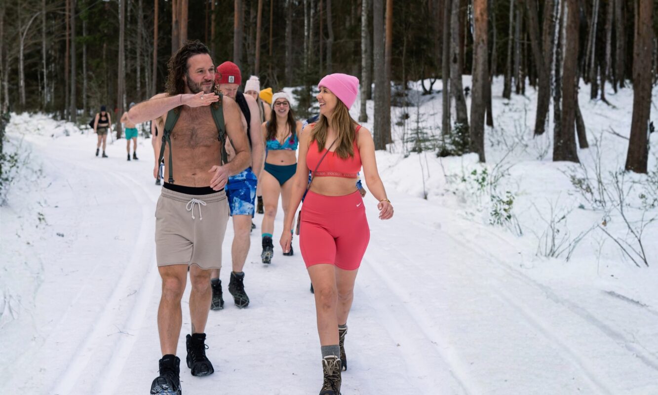 Group of retreat participants walking through a snowy forest at Shambala Gatherings in Sweden, enjoying an outdoor winter retreat surrounded by pine trees and snow.