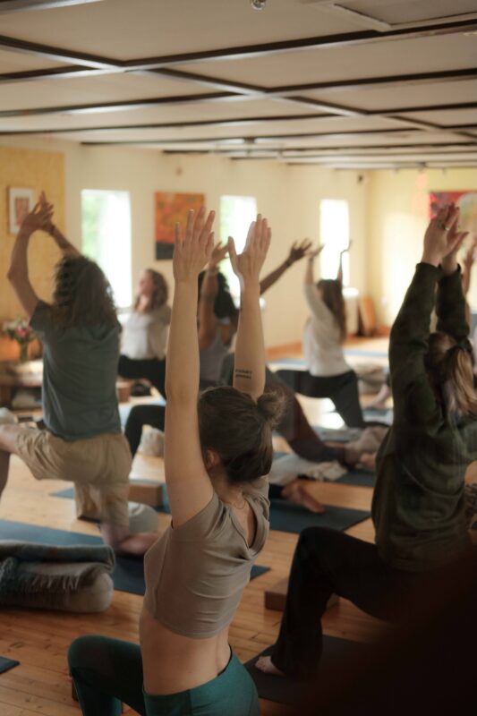 Yoga students raising their arms during a guided class.